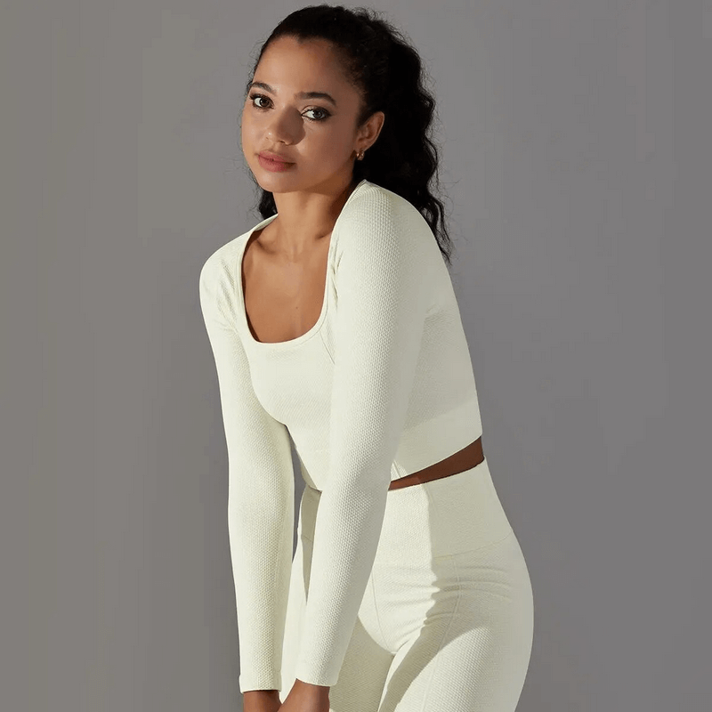Woman wearing a white seamless bodycon crop top with long sleeves, perfect for yoga, running, or cycling. Model SF1686.